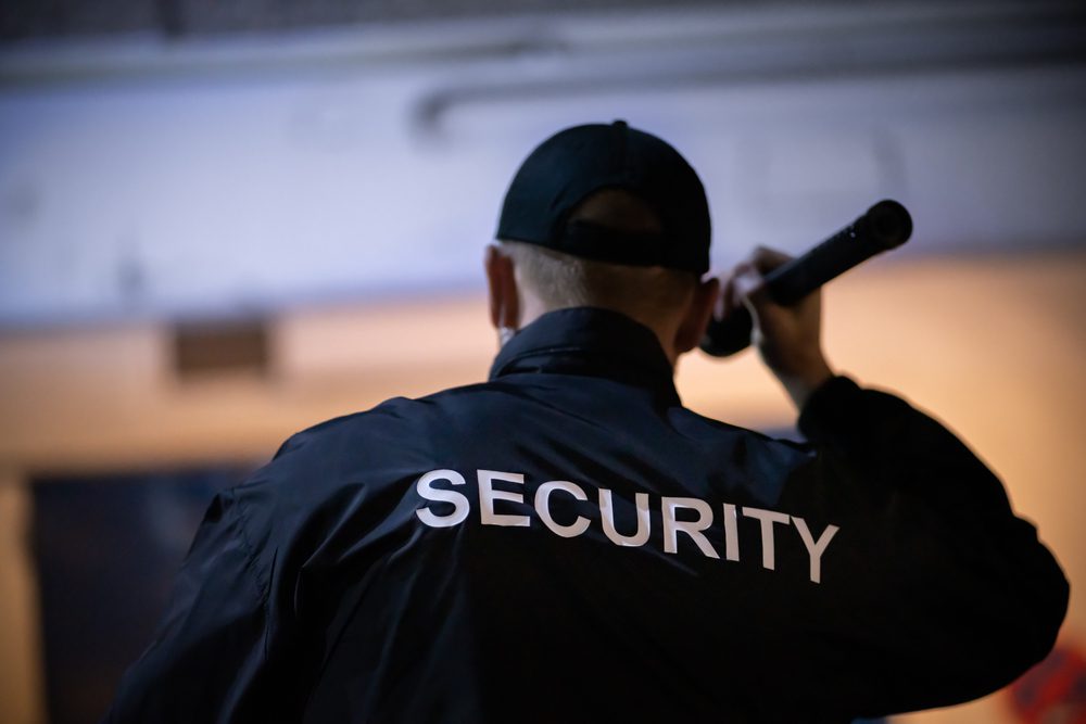 A security guard is holding a walkie talkie.